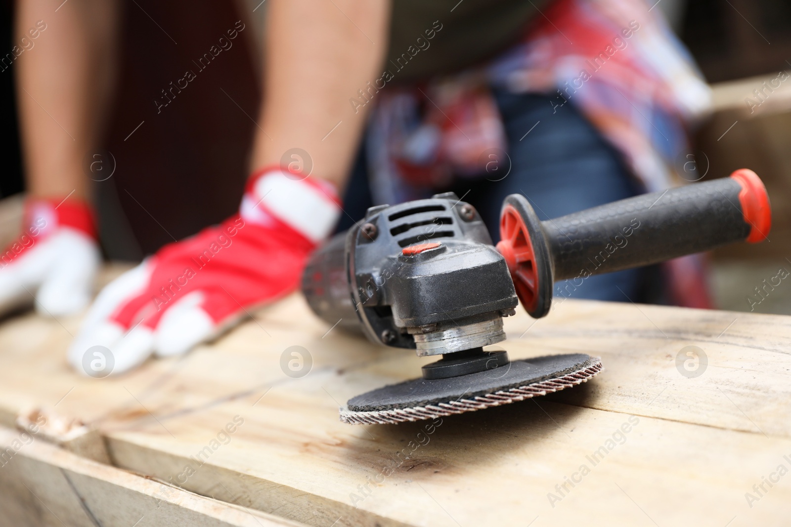 Photo of Man working with wood outdoors, focus on angle grinder