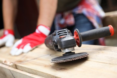 Photo of Man working with wood outdoors, focus on angle grinder