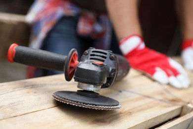 Man working with wood outdoors, focus on angle grinder