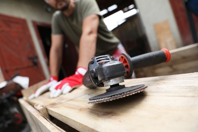 Photo of Man working with wood outdoors, focus on angle grinder