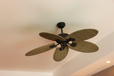 Photo of Modern ceiling fan indoors, low angle view