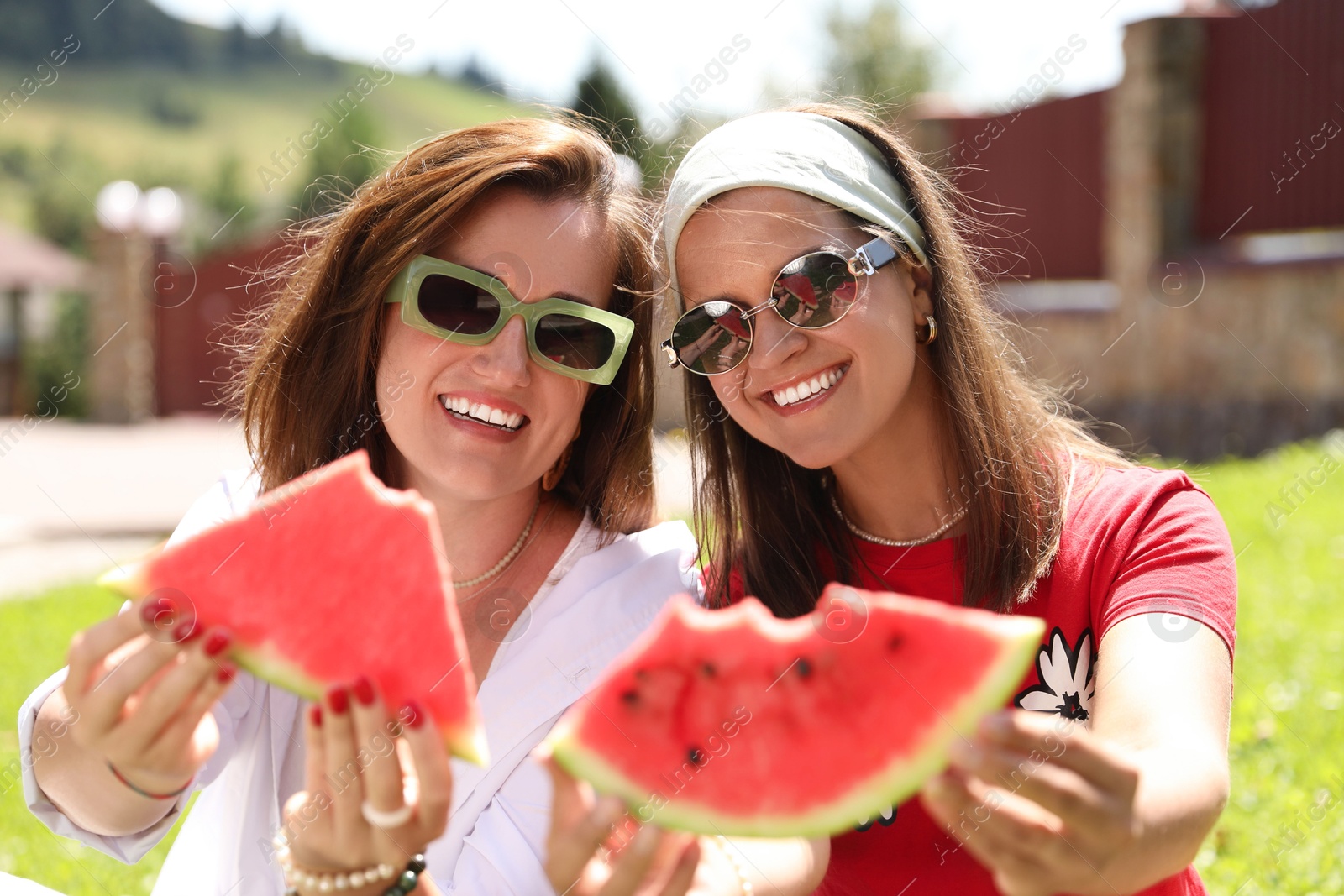 Photo of Happy women holding slices of juicy watermelon outdoors