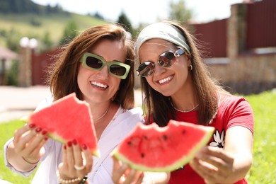 Happy women holding slices of juicy watermelon outdoors