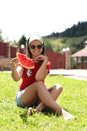 Photo of Happy woman holding slice of juicy watermelon on green grass outdoors