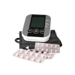 Blood pressure monitor and pills in blisters isolated on white