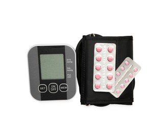 Photo of Blood pressure monitor and pills in blisters isolated on white, top view