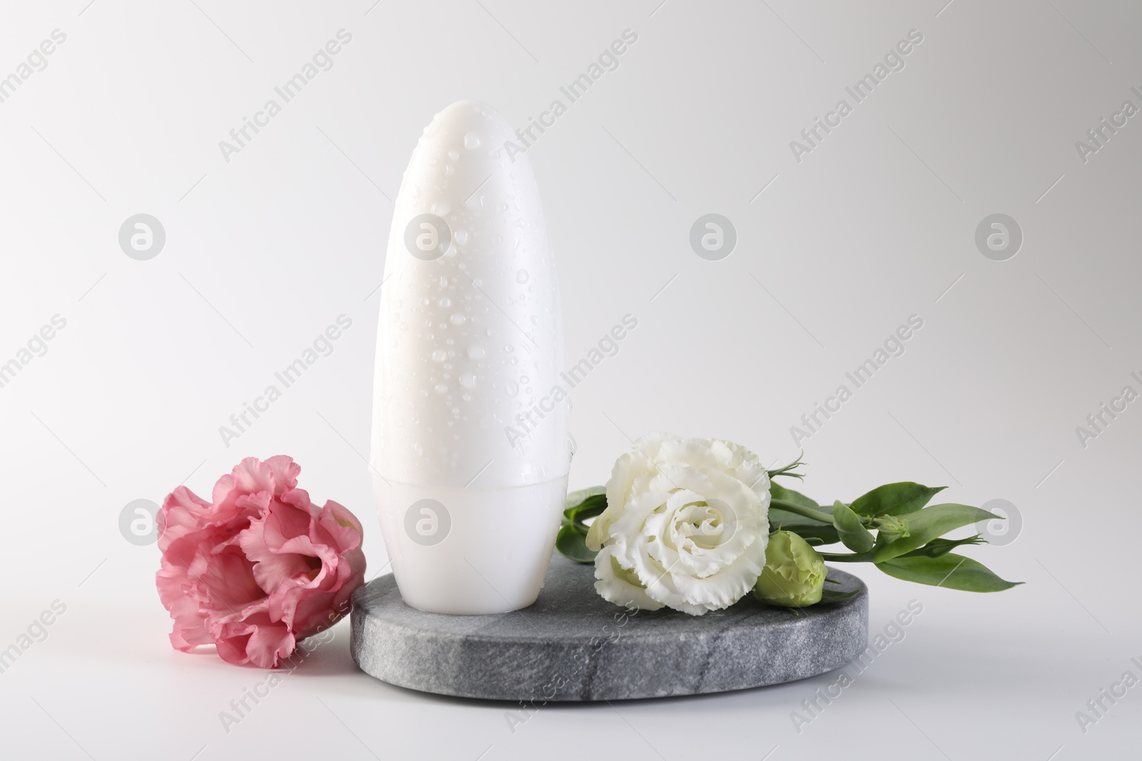 Photo of Roll-on deodorant and beautiful eustoma flowers on white background