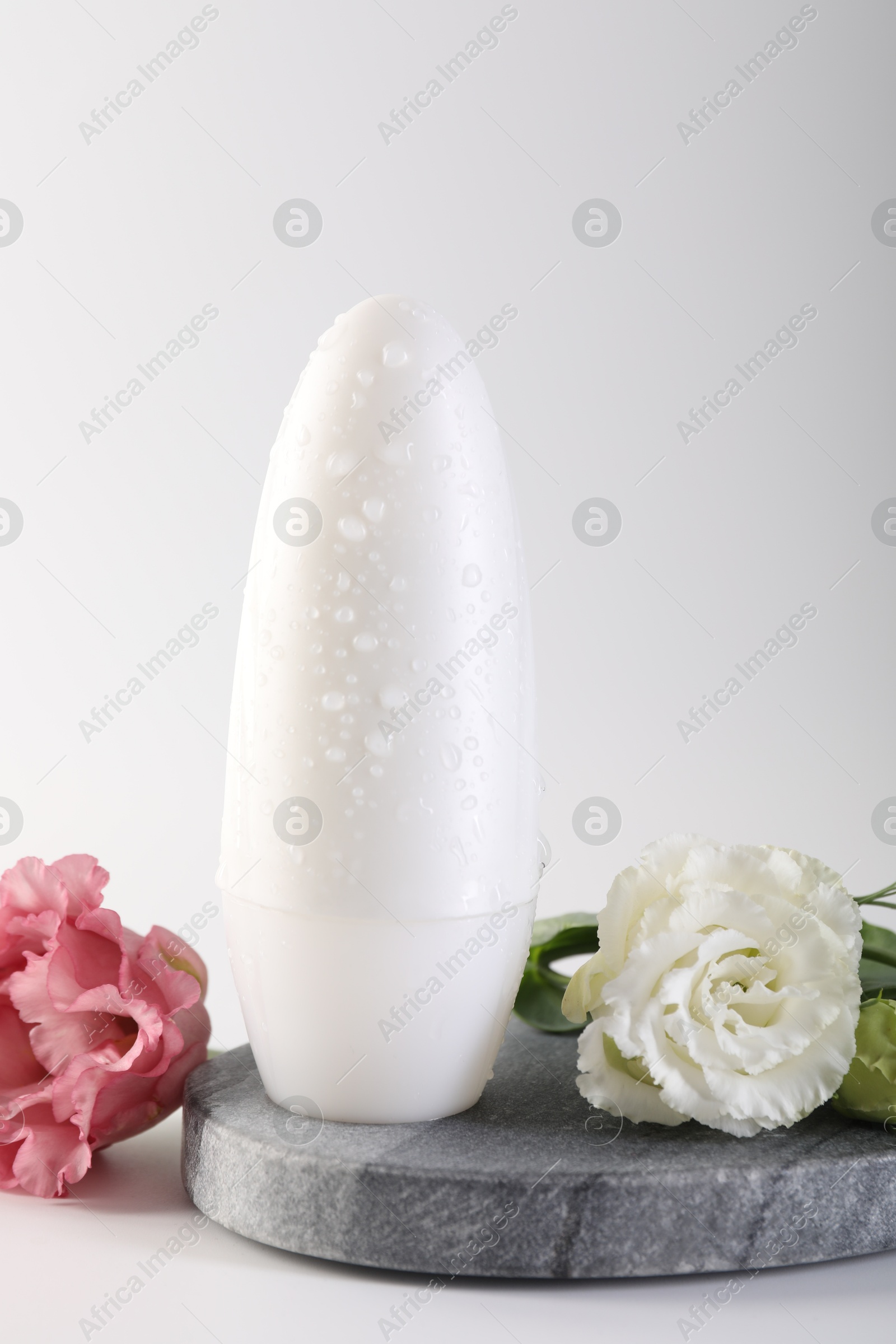 Photo of Roll-on deodorant and beautiful eustoma flowers on white background