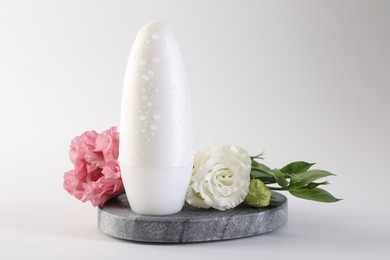 Photo of Roll-on deodorant and beautiful eustoma flowers on white background