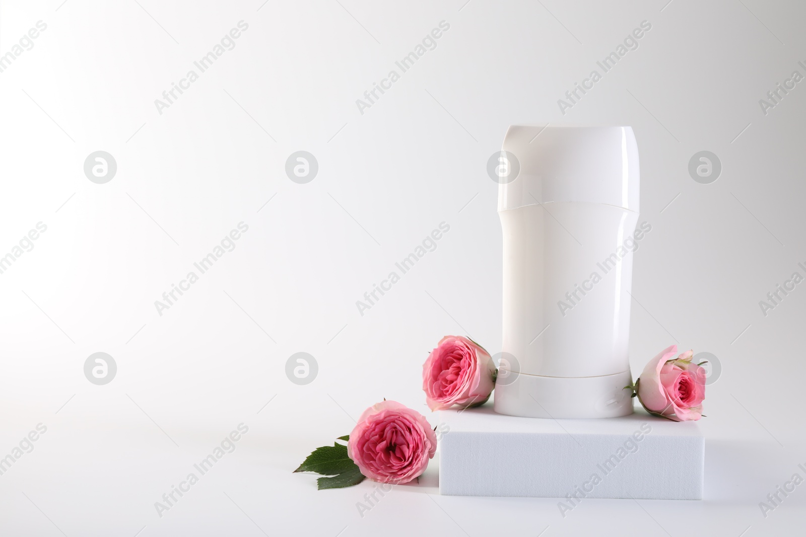 Photo of Solid deodorant and beautiful rose flowers on white background, space for text