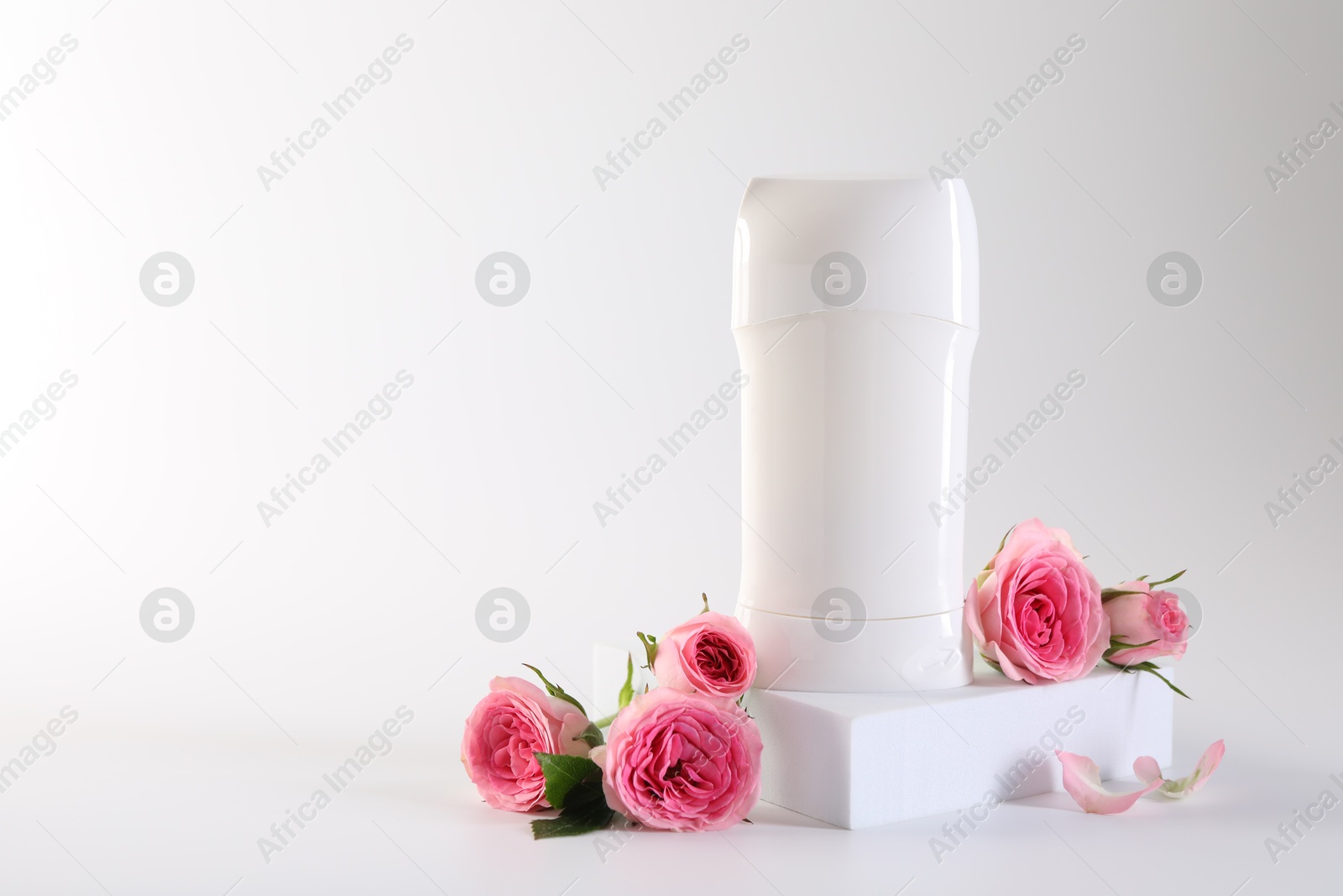 Photo of Solid deodorant and beautiful rose flowers on white background, space for text