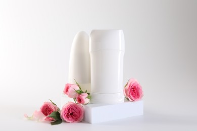 Photo of Different deodorants and beautiful rose flowers on white background