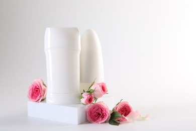 Photo of Different deodorants beautiful rose flowers on white background, space for text