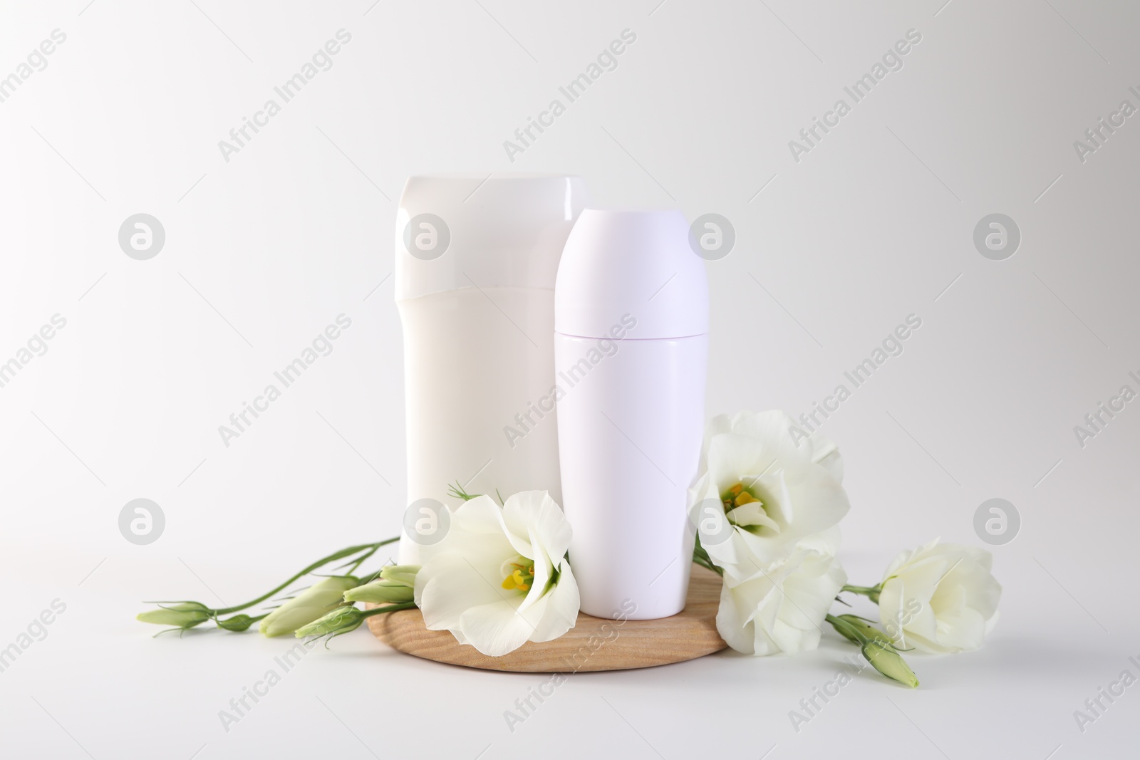 Photo of Different deodorants and beautiful eustoma flowers on white background