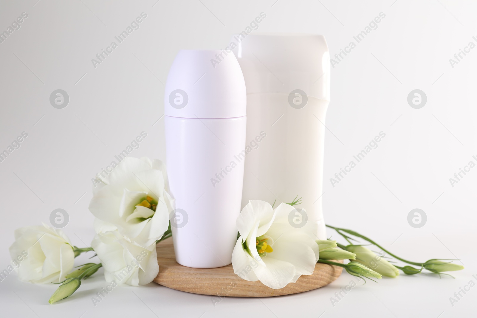 Photo of Different deodorants and beautiful eustoma flowers on white background