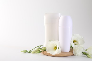 Photo of Different deodorants and beautiful eustoma flowers on white background, space for text