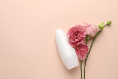 Photo of Roll-on deodorant and beautiful eustoma flowers on beige background, flat lay. Space for text