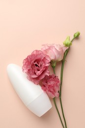 Photo of Roll-on deodorant and beautiful eustoma flowers on beige background, flat lay