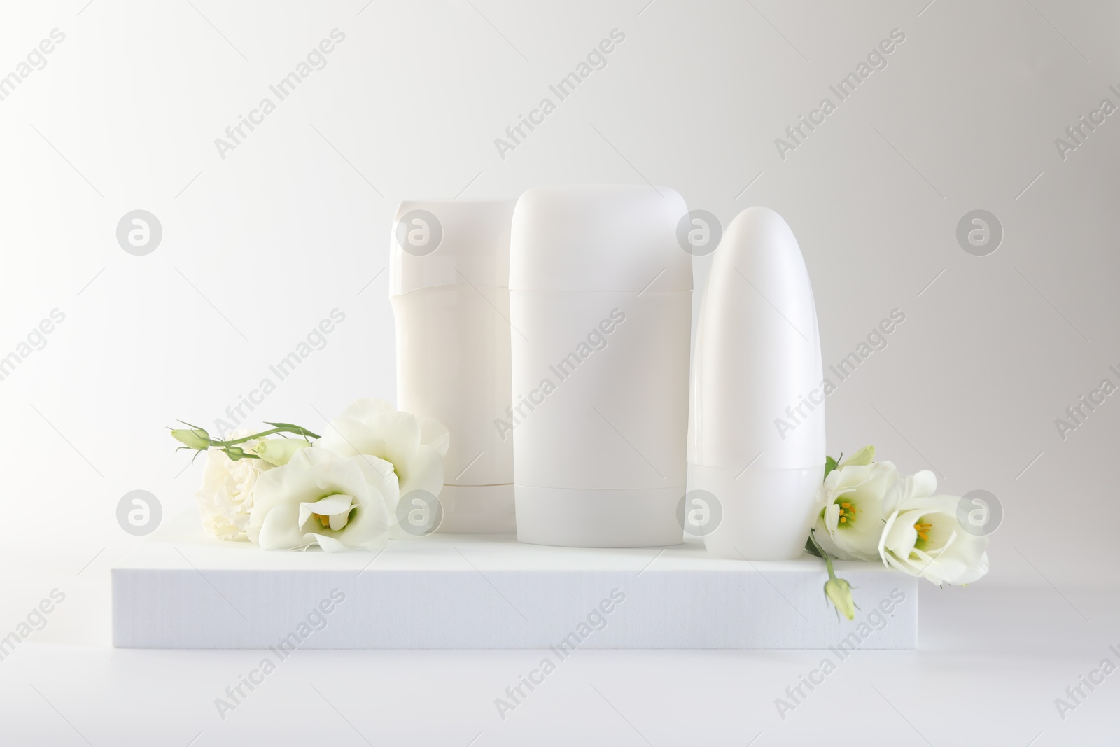 Photo of Different deodorants and beautiful eustoma flowers on white background