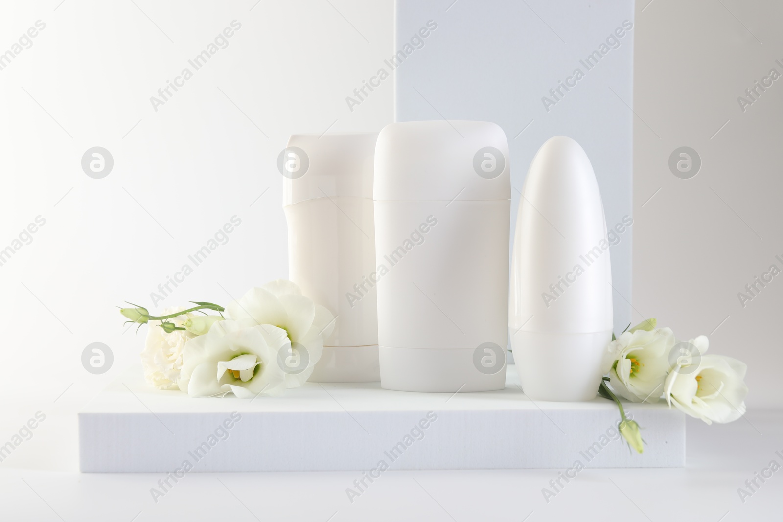 Photo of Different deodorants and beautiful eustoma flowers on white background