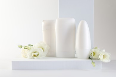 Photo of Different deodorants and beautiful eustoma flowers on white background