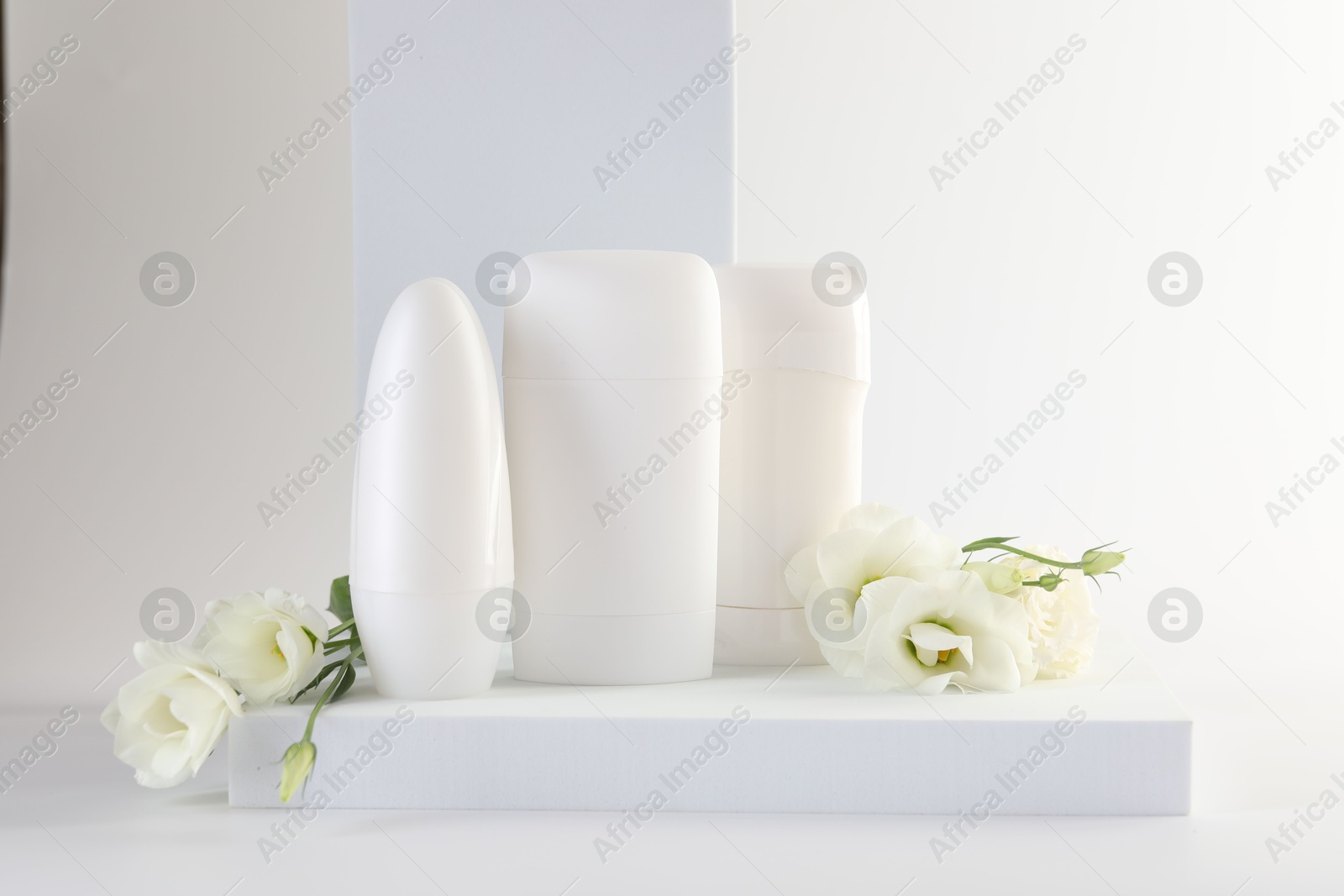 Photo of Different deodorants and beautiful eustoma flowers on white background