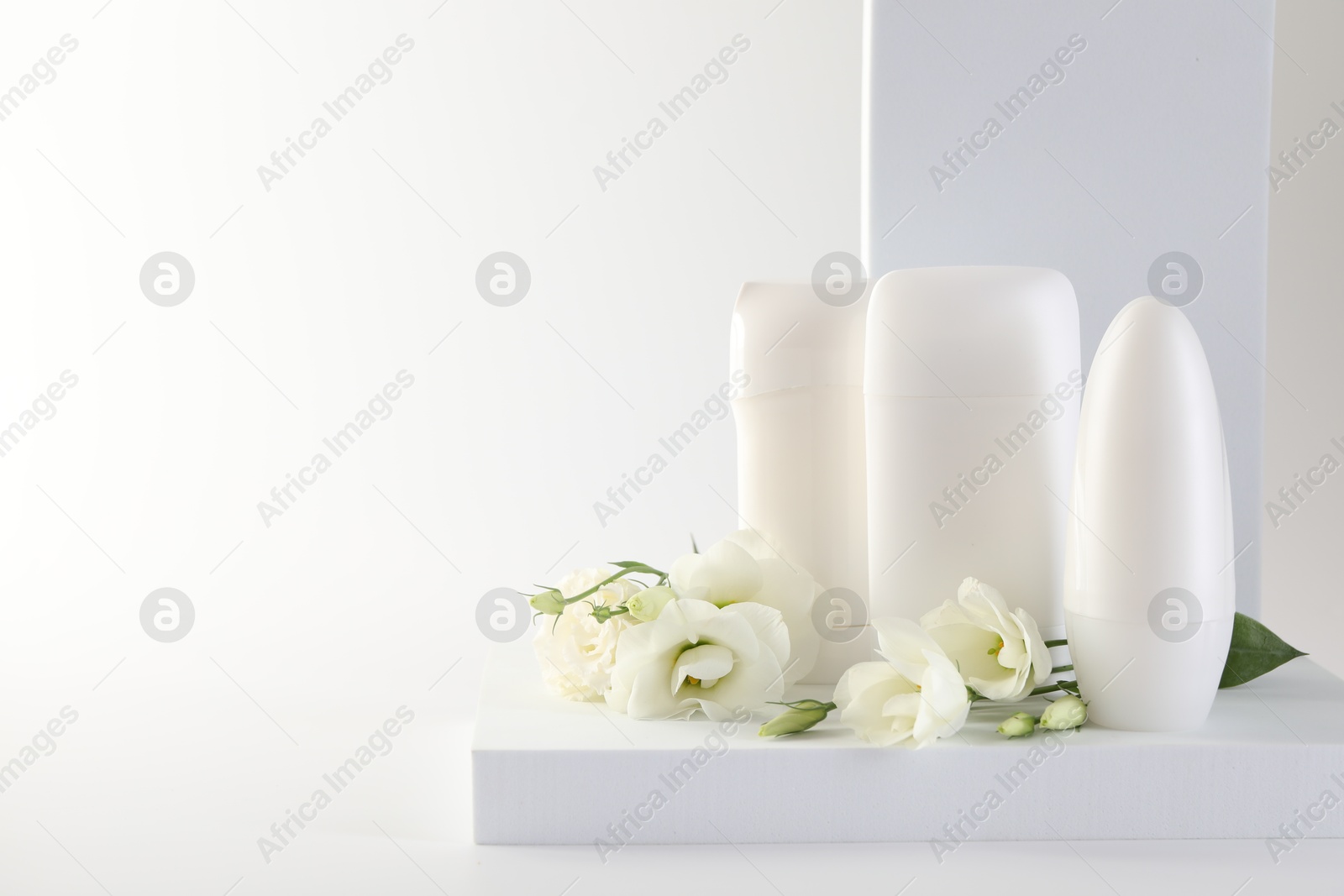 Photo of Different deodorants and beautiful eustoma flowers on white background, space for text