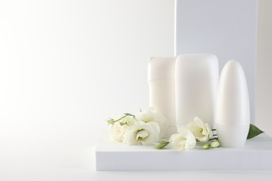 Photo of Different deodorants and beautiful eustoma flowers on white background, space for text