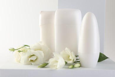 Photo of Different deodorants and beautiful eustoma flowers on white background