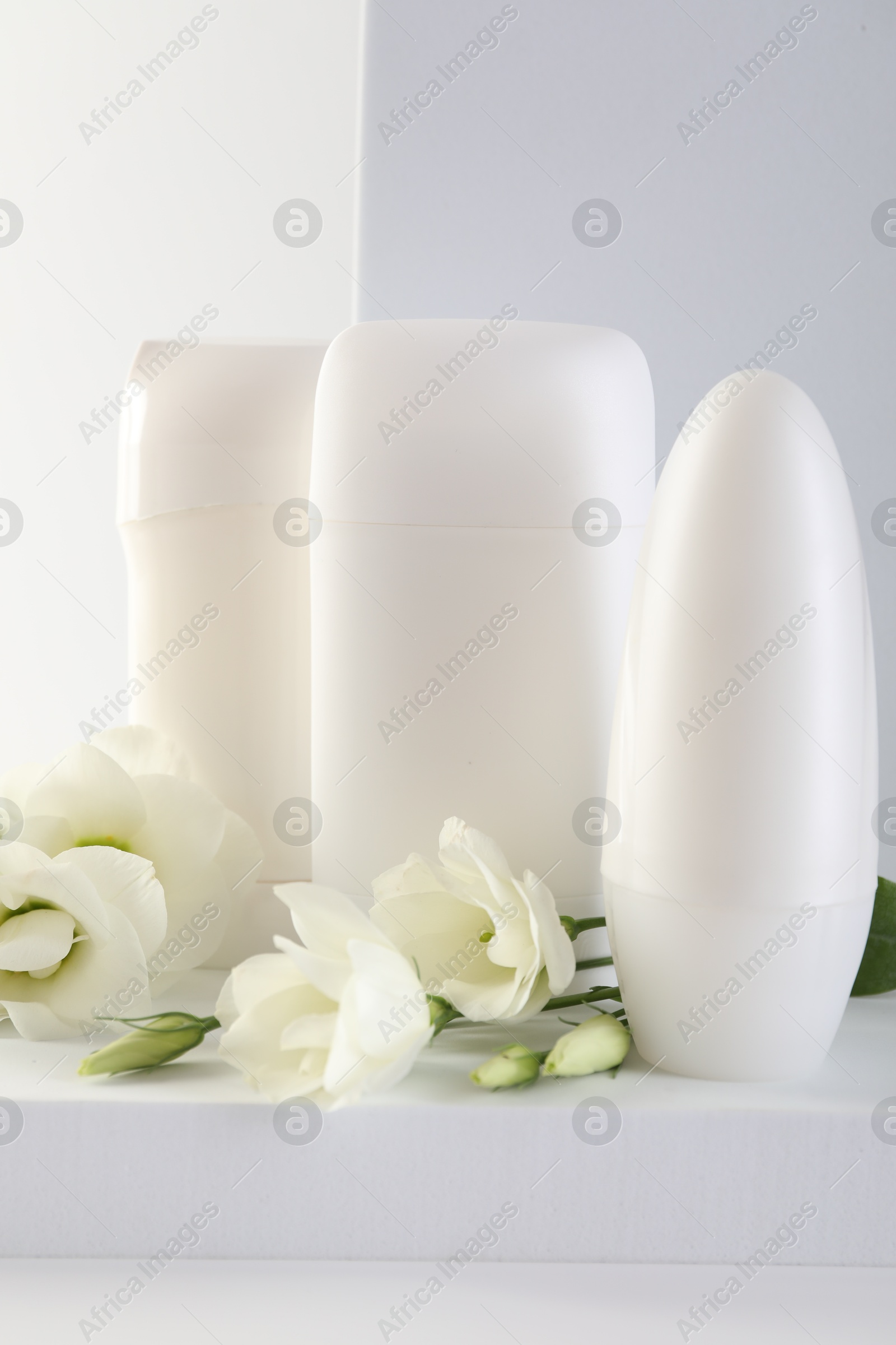 Photo of Different deodorants and beautiful eustoma flowers on white background