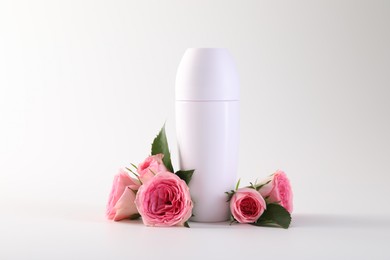 Photo of Roll-on deodorant and beautiful rose flowers on white background