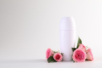 Photo of Roll-on deodorant and beautiful rose flowers on white background, space for text