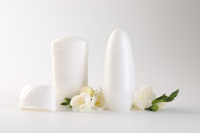 Photo of Different deodorants and beautiful eustoma flowers on white background