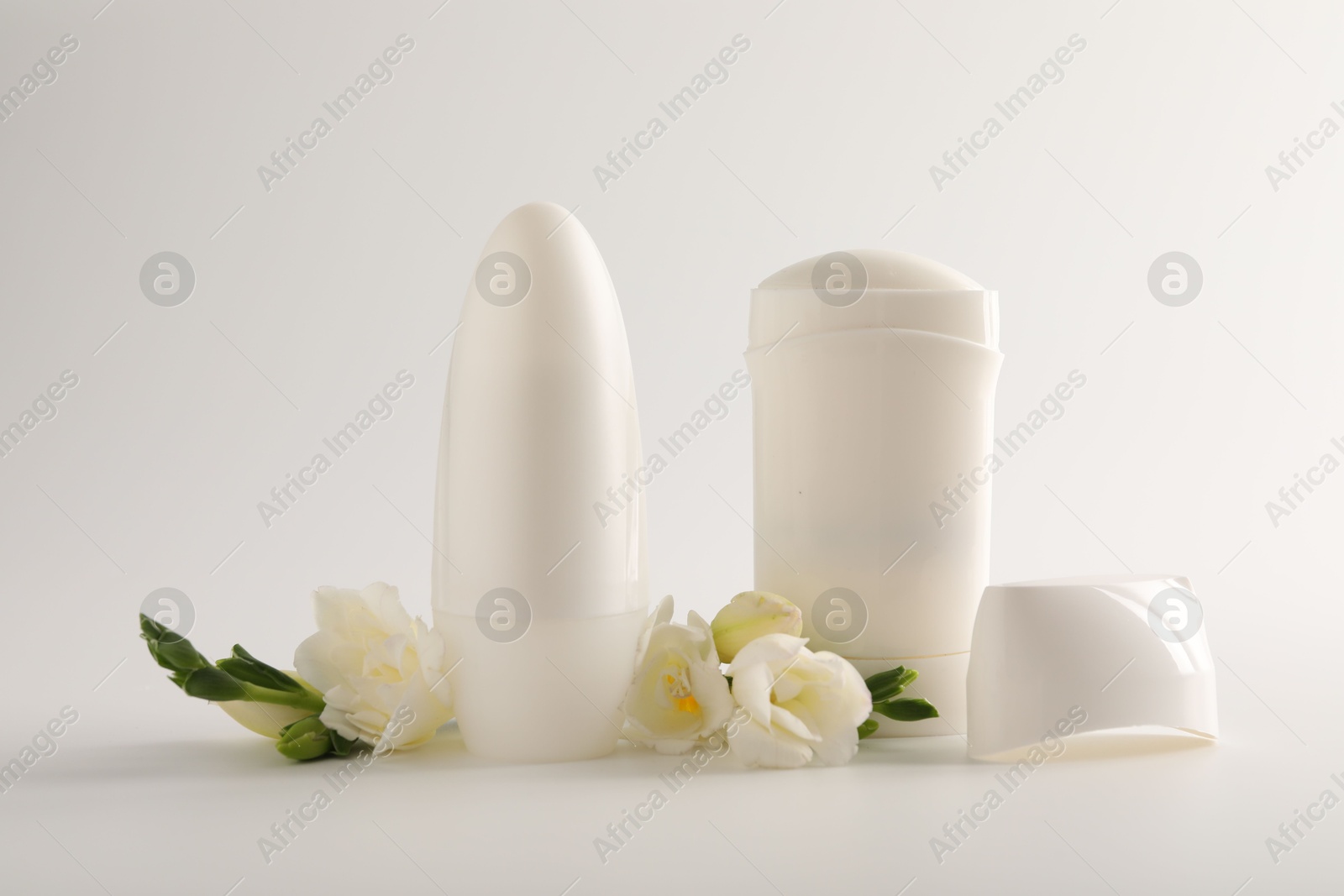 Photo of Different deodorants and beautiful eustoma flowers on white background