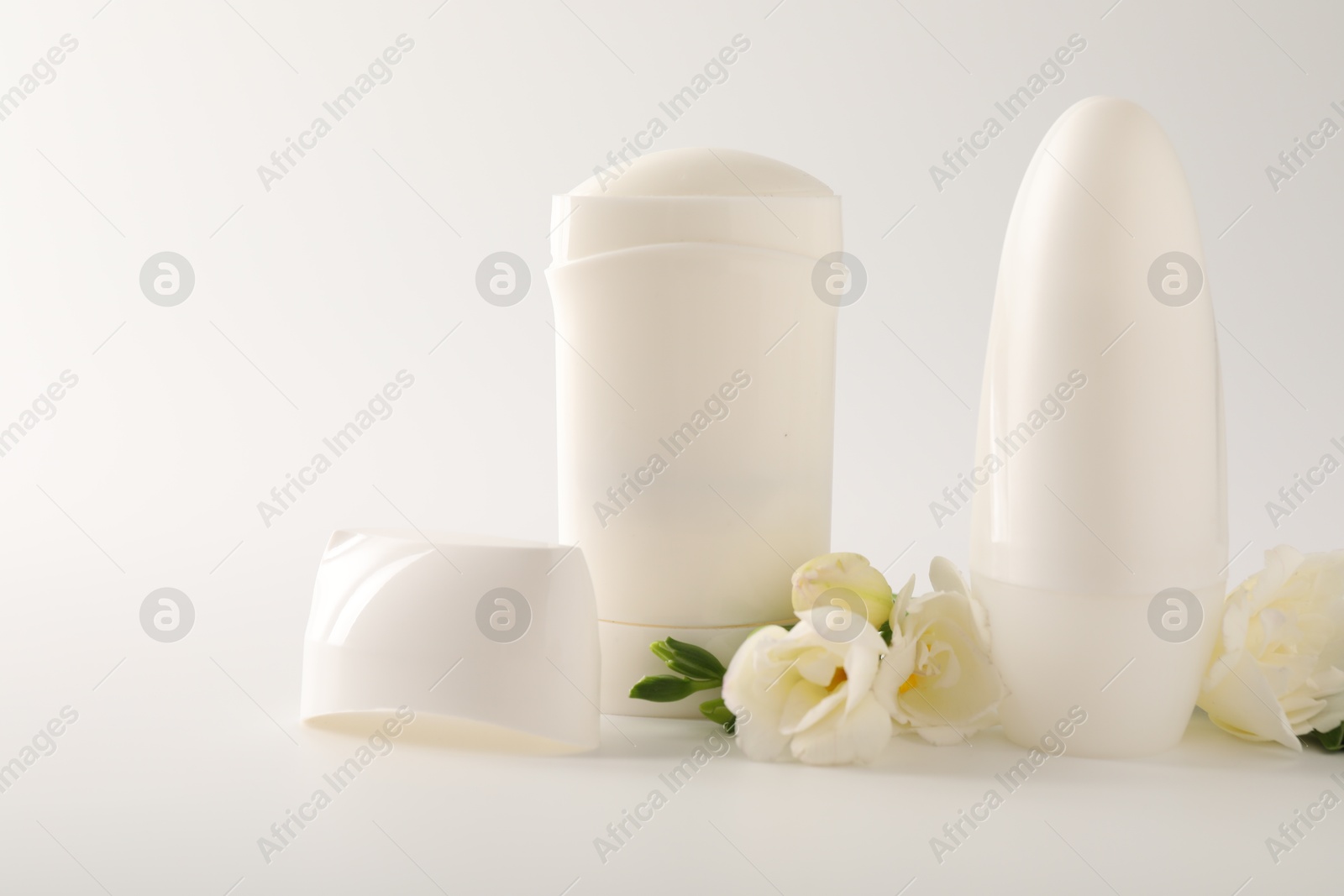 Photo of Different deodorants and beautiful eustoma flowers on white background