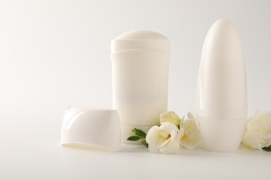 Photo of Different deodorants and beautiful eustoma flowers on white background