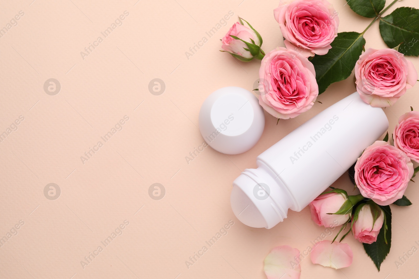 Photo of Roll-on deodorant and beautiful rose flowers on beige background, flat lay. Space for text