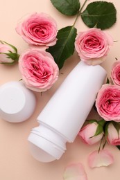 Photo of Roll-on deodorant and beautiful rose flowers on beige background, flat lay