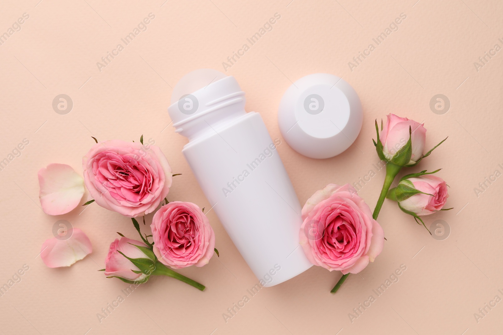 Photo of Roll-on deodorant and beautiful rose flowers on beige background, flat lay