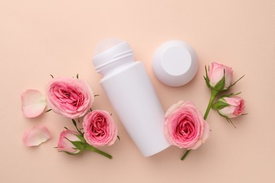 Photo of Roll-on deodorant and beautiful rose flowers on beige background, flat lay