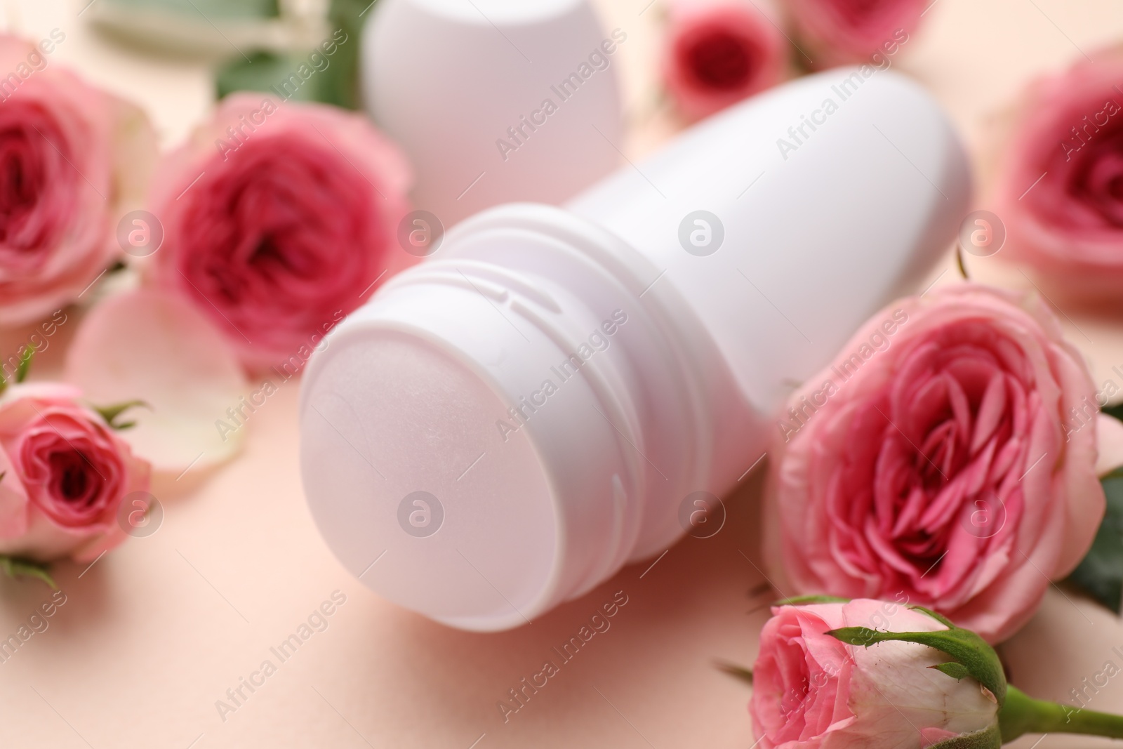 Photo of Roll-on deodorant and beautiful rose flowers on beige background, closeup