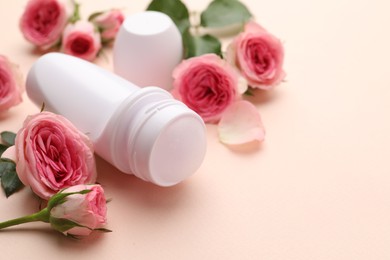 Photo of Roll-on deodorant and beautiful rose flowers on beige background, closeup