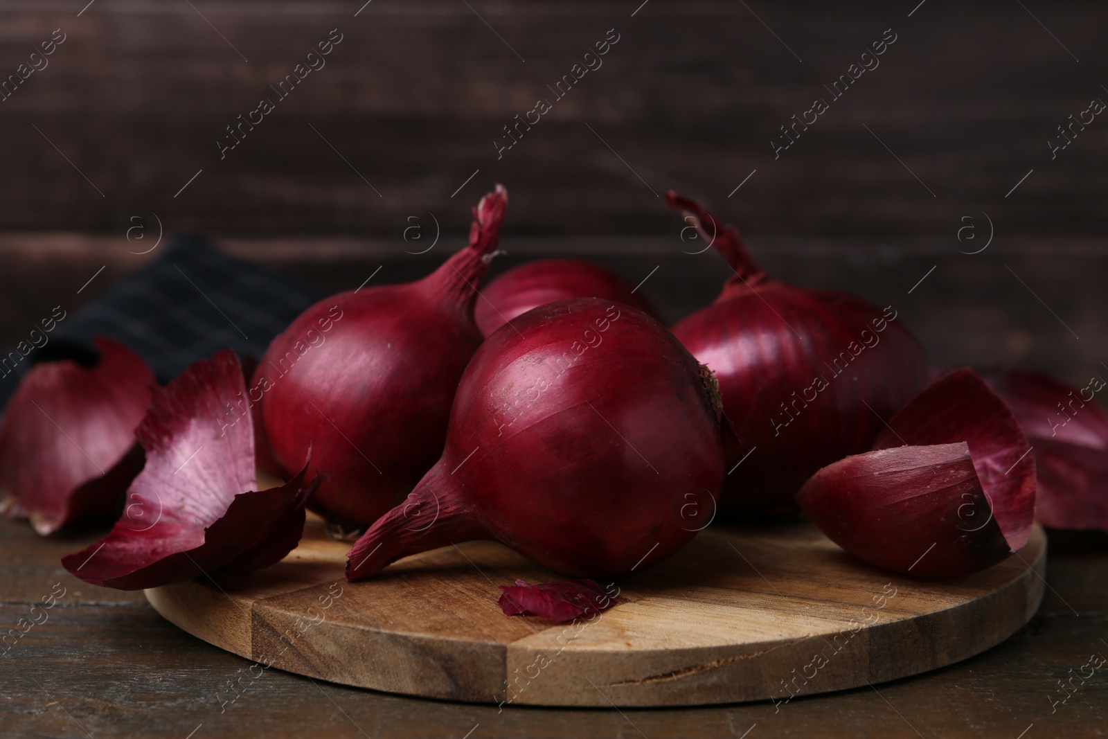 Photo of Fresh onions with peels on wooden table, closeup