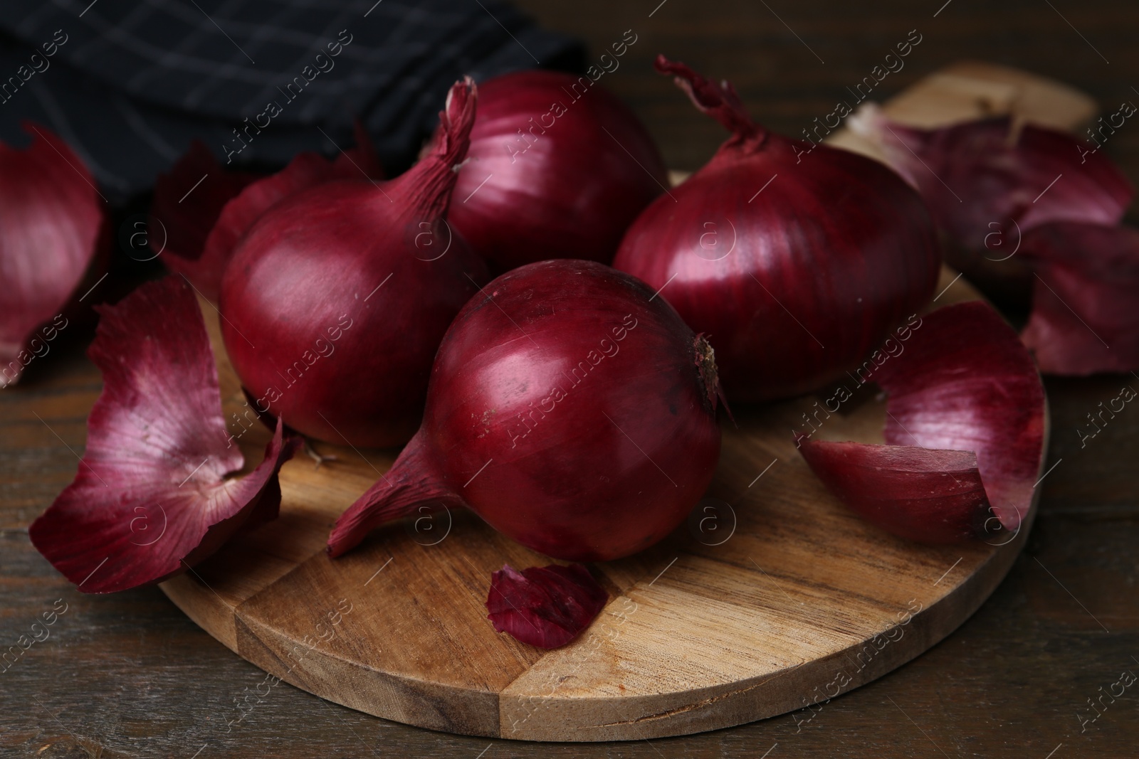 Photo of Fresh onions with peels on wooden table, closeup