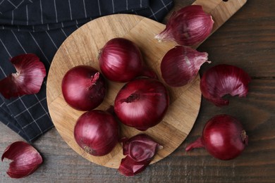 Photo of Fresh onions with peels on wooden table, flat lay