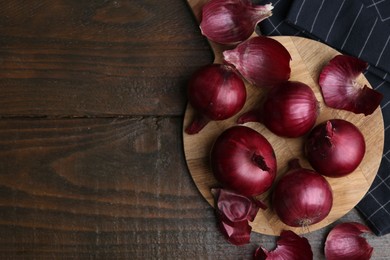 Photo of Fresh onions with peels on wooden table, flat lay. Space for text