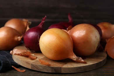 Photo of Fresh onions with peels on wooden table, closeup