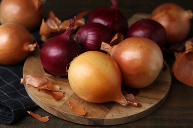 Photo of Fresh onions with peels on wooden table, closeup