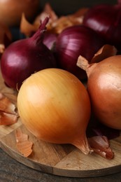 Photo of Fresh onions with peels on wooden table, closeup