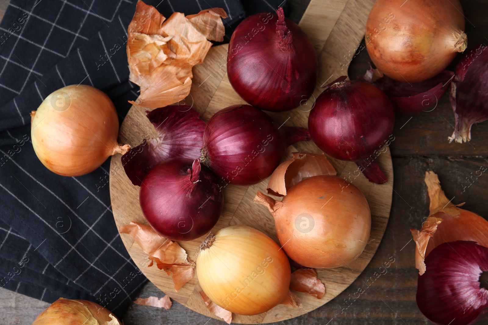 Photo of Fresh onions with peels on wooden table, flat lay